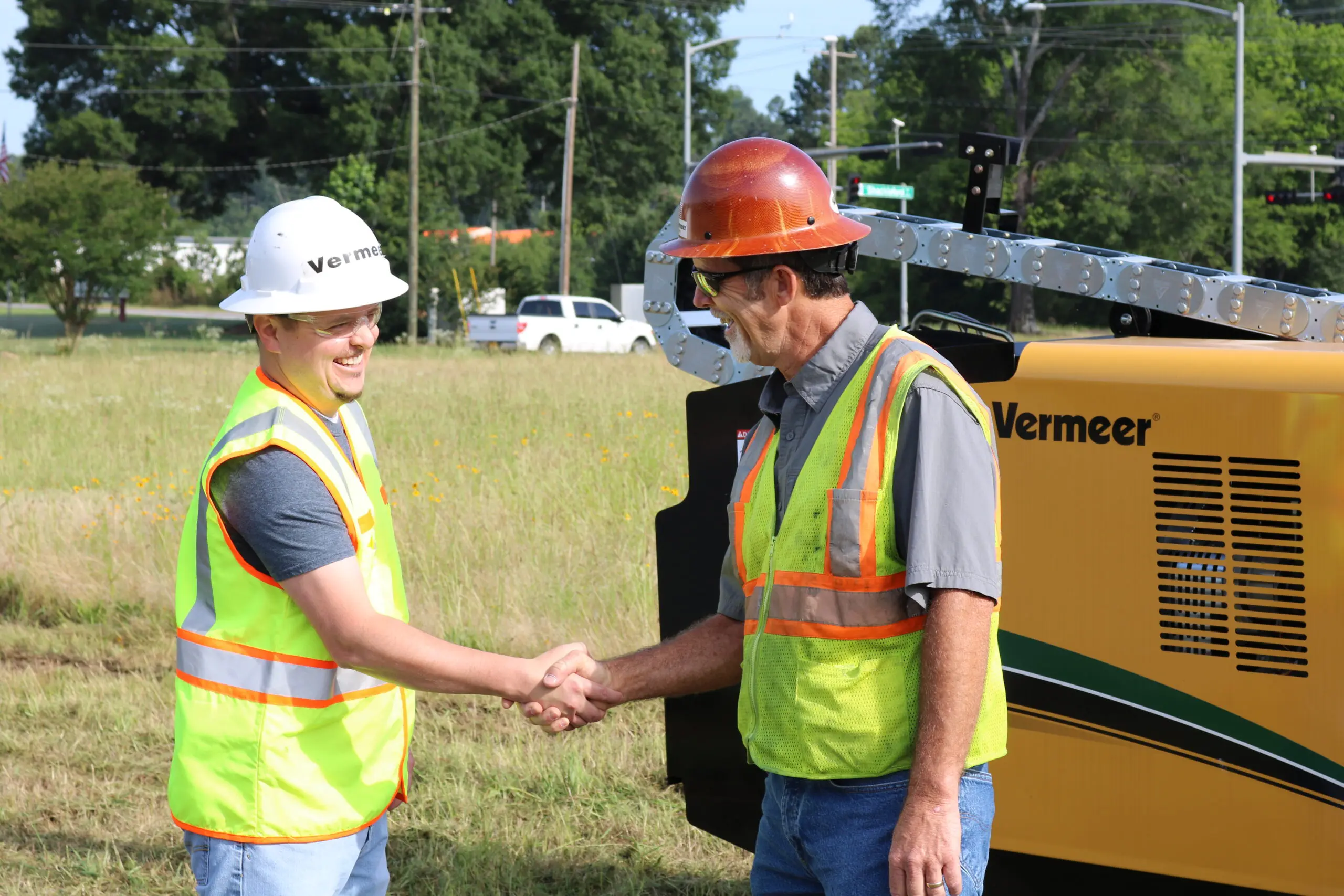 Two men shaking hands in front of Vermeer drill